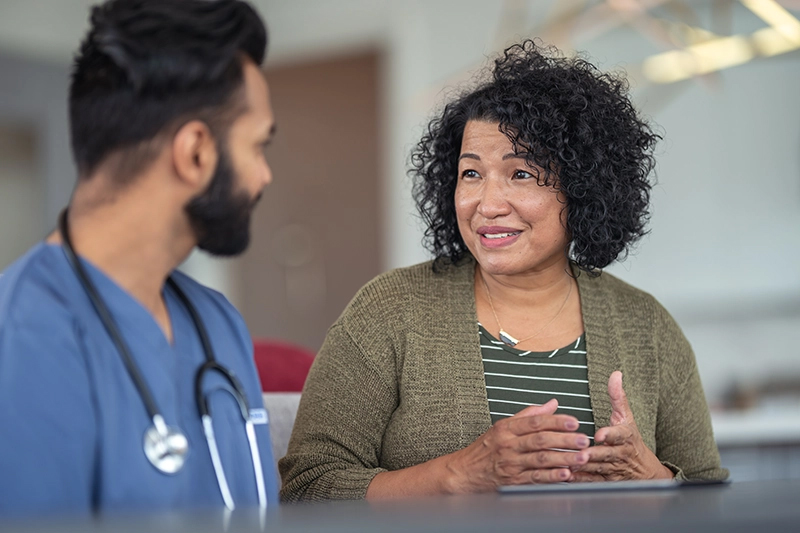 A woman's questions being answered by a male care coordinator in blue scrubs