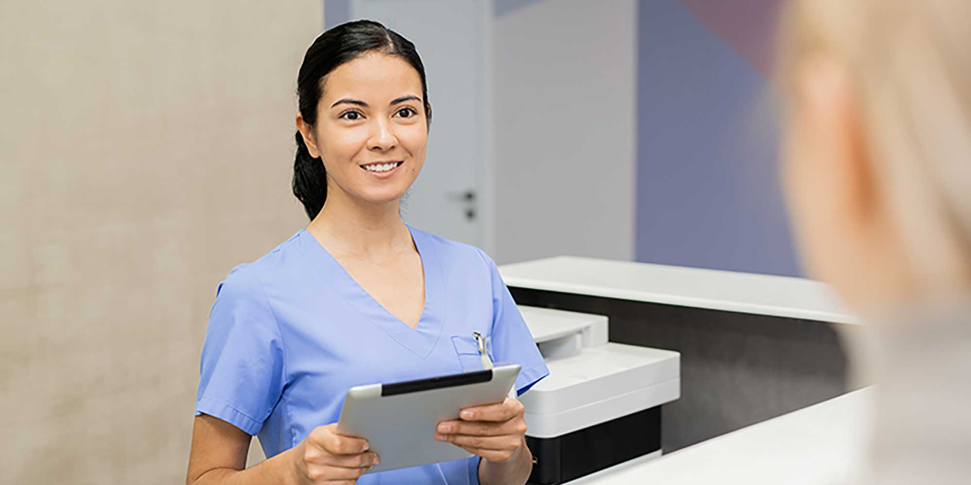 A provider holds a tablet while visiting a patient
